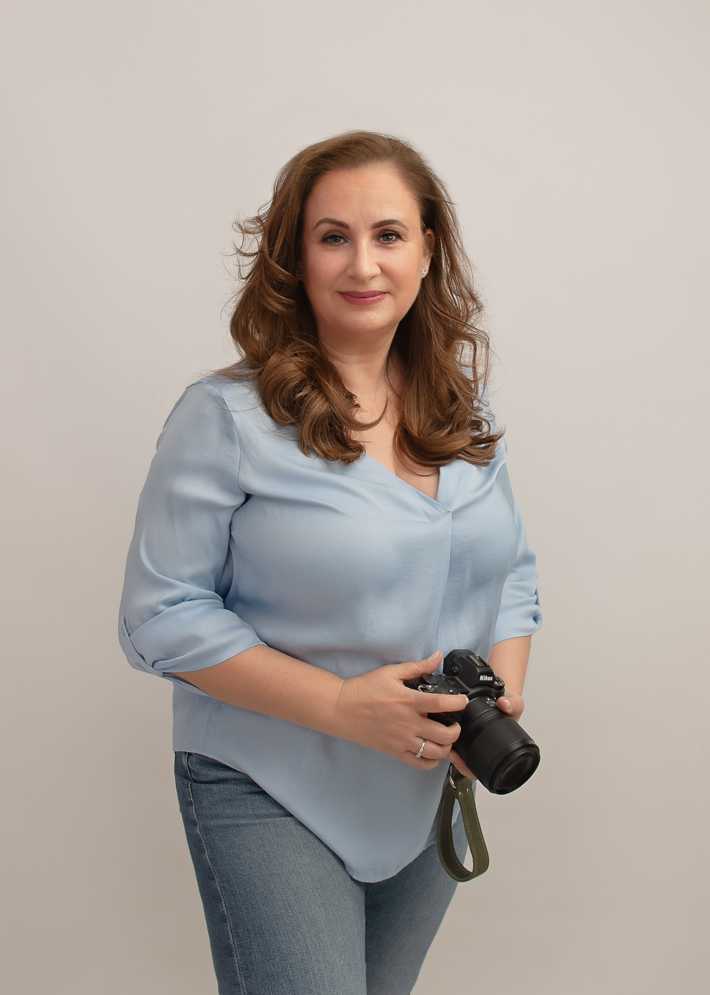 Mariana holding her camera, wearing a light blue blouse