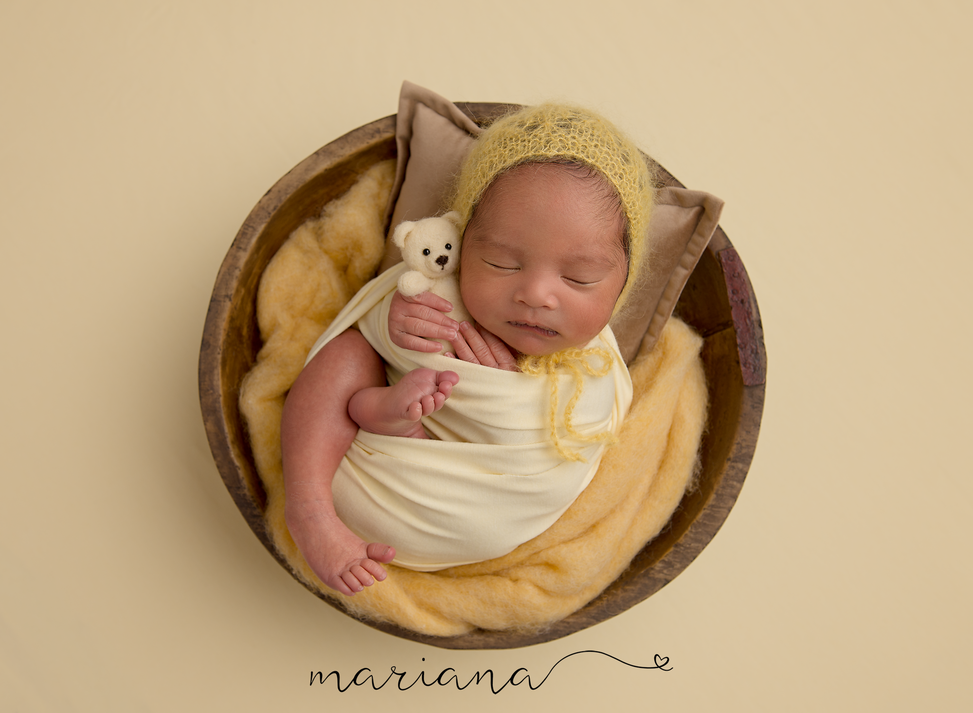 Sleeping newborn in an ivory wrap with yellow accents
