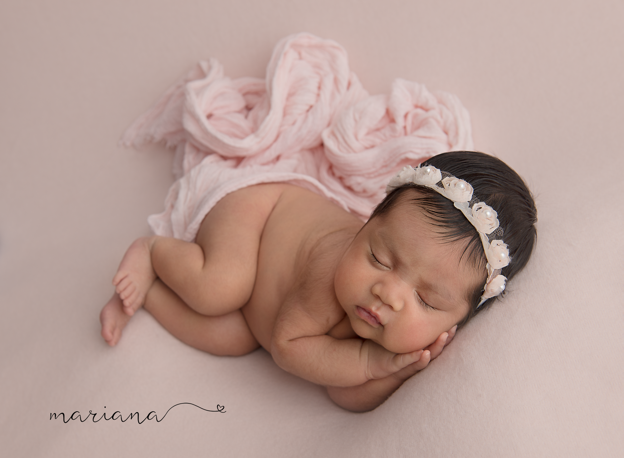 Sleeping newborn on soft pink with a floral headband