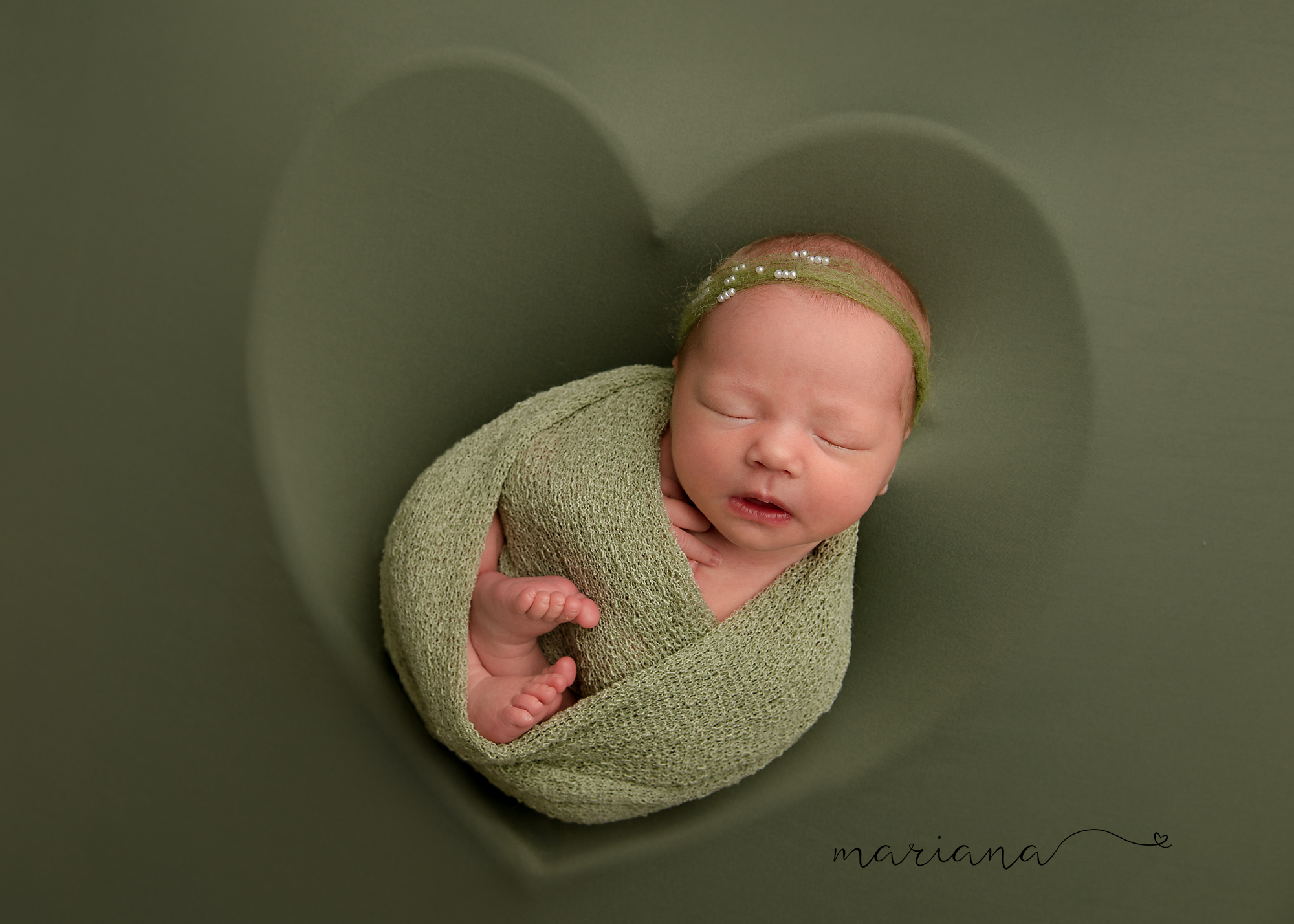 Newborn wrapped in sage green on a green background