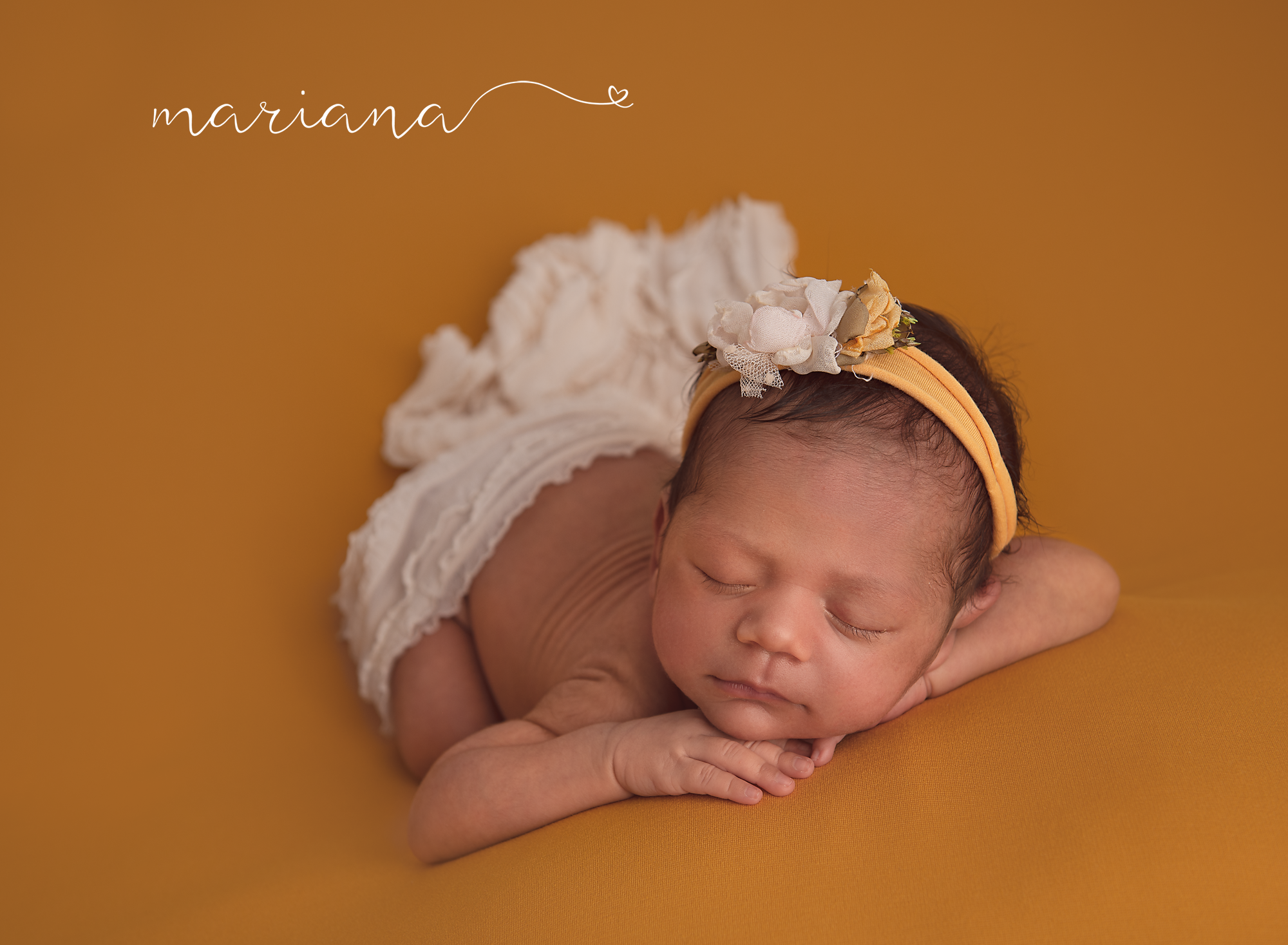 Sleeping newborn on warm yellow with a floral headband