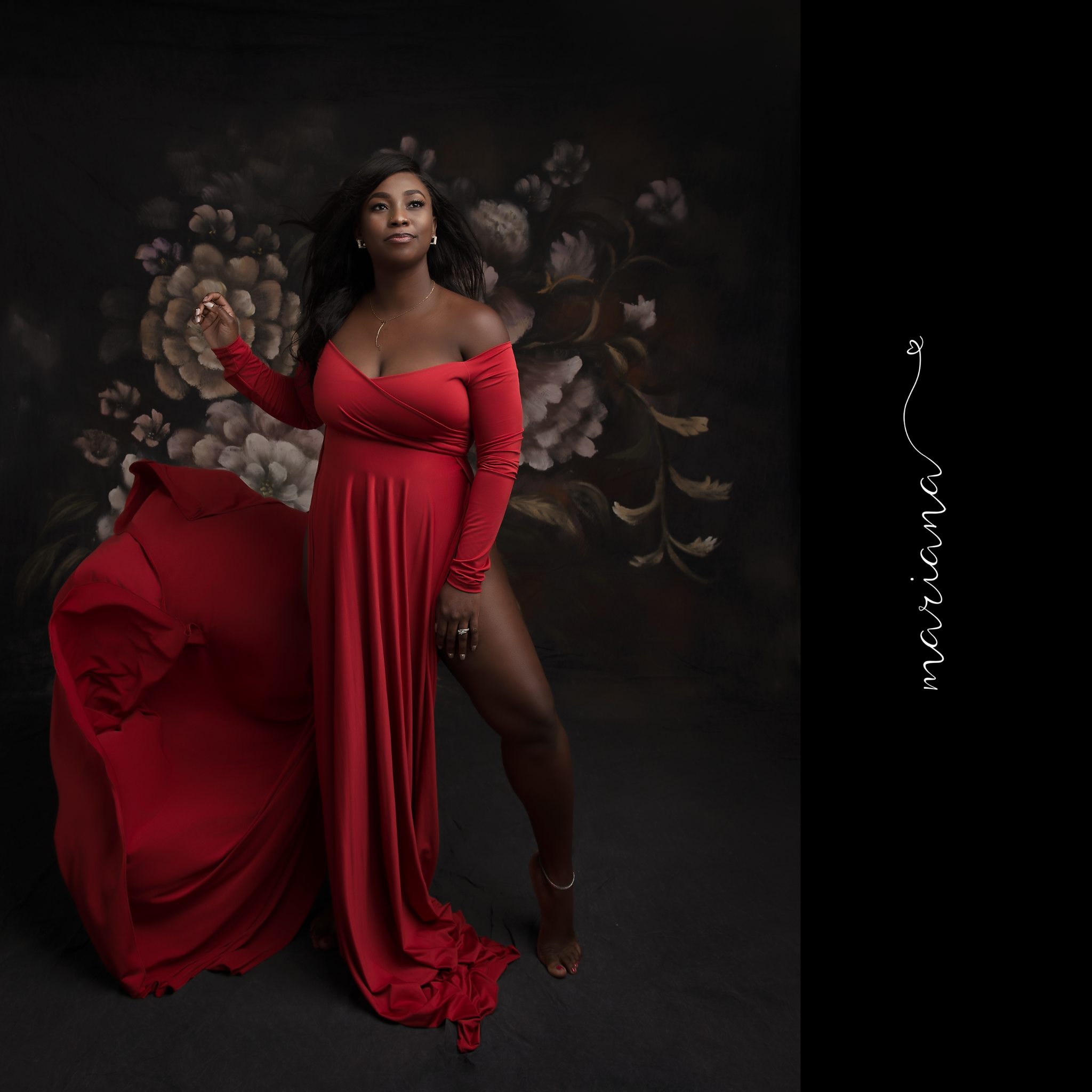 Woman in a flowing red gown against a dark floral backdrop